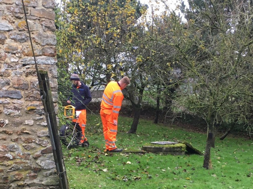 Two men in hi-vis suits carrying out the existing drainage survey at Ley Farm Cottages
